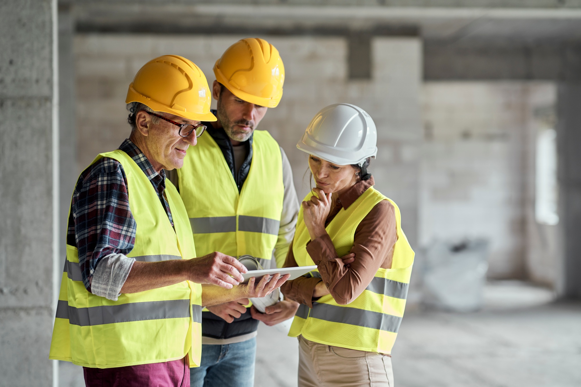 Three caucasian engineers discussing over digital tablet on the construction site